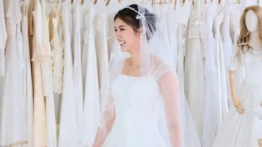 Asyalı kadın onu yeni gelinlik üzerinde çalışıyor. Harika gülümseme ve mutluluk.