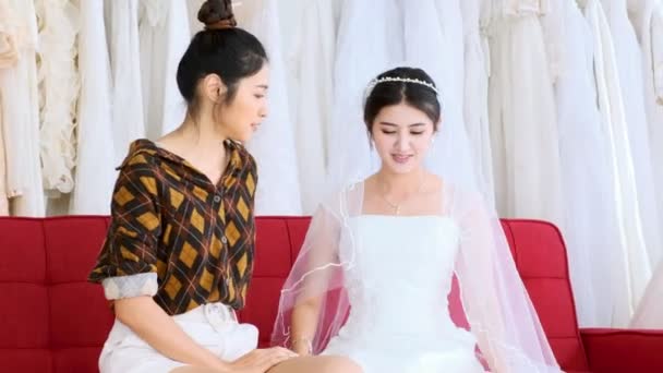 若い結婚式ドレス デザイナー作業 若いアジアの女性は 花嫁のドレス 赤いソファの上に座っての顧客に話しています スモール ビジネス コンセプト — ストック動画