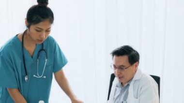 Genç tıbbi kadın Doktor Röntgen filmi ile konuşurken, masanın üstüne oturan üst düzey Asya adam tıp doktoru. Genç tıp doktoru kariyer kavramı. 