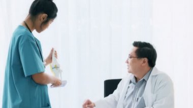 Genç tıbbi kadın doktorla konuşurken, masanın üstüne oturan üst düzey Asya adam tıp doktoru kadar kemik sahte inceleyin. Genç tıp doktoru kariyer kavramı.