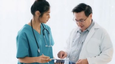 Üst düzey Asya adam tıp doktoru ayakta, notlarını incelemek genç tıbbi kadın doktorla konuşuyor. Genç tıp doktoru kariyer kavramı.
