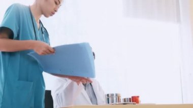 Doktor tıbbi hap tutan genç tıbbi kadın konuşurken, masanın üstüne oturan üst düzey Asya adam tıp doktoru. Genç tıp doktoru kariyer kavramı.