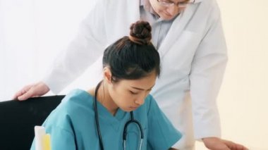 Doktor tıbbi hap tutan genç tıbbi kadın konuşurken, masanın üstüne oturan üst düzey Asya adam tıp doktoru. Genç tıp doktoru kariyer kavramı.