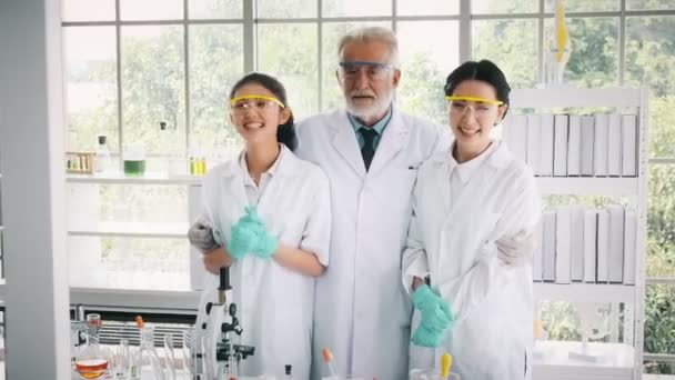 白のコートで 抱擁を与える彼女の年配の男性と 実験での成功で祝う若いアジアの化学者 科学のコンセプト — ストック動画