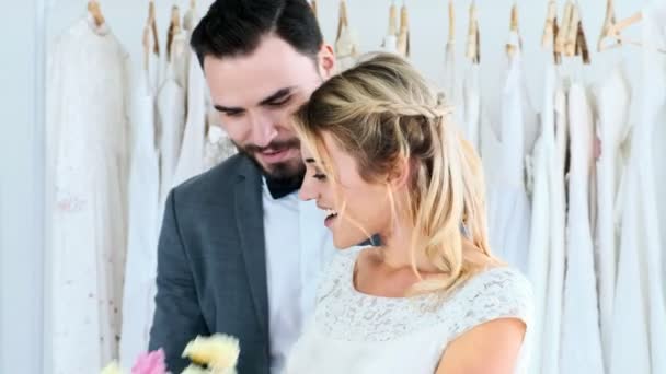 浪漫的一对新婚夫妇在昂贵的服装店 白色的男人和女人在新娘礼服 男人给女人花 浪漫的年轻夫妇的概念 — 图库视频影像