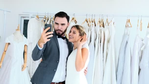 浪漫的一对新婚夫妇在昂贵的服装店 白色男女穿着新娘礼服 视频用手机给朋友打电话 浪漫的年轻夫妇的概念 — 图库视频影像