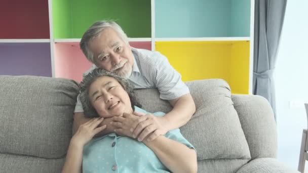 老夫妇坐在客厅里拥抱在一起 退休的老亚洲男女 说话牵手 快乐的微笑 老年人生活方式理念 — 图库视频影像
