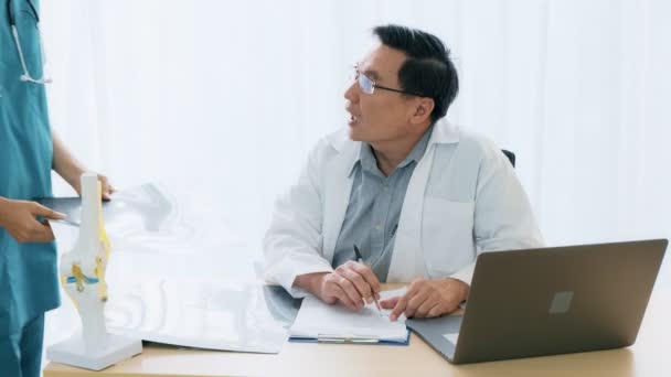 Médico Asiático Sênior Sentado Sua Mesa Conversando Com Uma Jovem — Vídeo de Stock