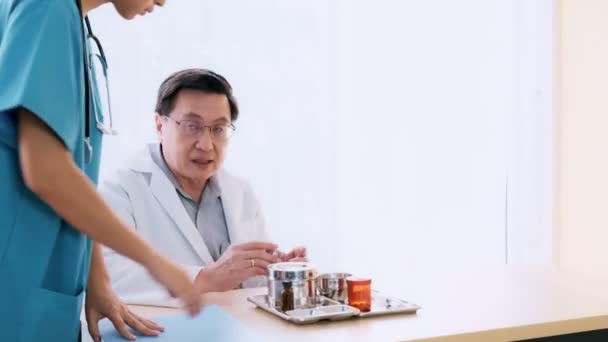 Ein Älterer Asiatischer Arzt Sitzt Auf Seinem Schreibtisch Und Spricht — Stockvideo