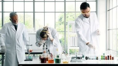 Bir laboratuarda çalışan kimyagerler grubudur. Beyaz genç erkek ve dişi kimyagerler ile mikroskop arıyorum birlikte laboratuarda, çalışan üst düzey beyaz kimyager. Bilim kavramı.