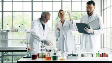Bir laboratuarda çalışan kimyagerler grubudur. Genç erkek ve dişi kimyagerler notlar alarak birlikte laboratuarda, çalışan üst düzey beyaz kimyager ile beyaz. Bilim kavramı.