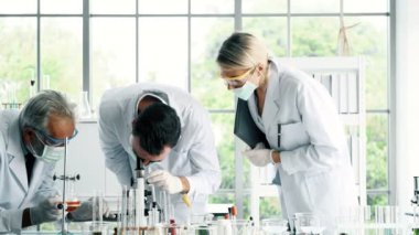Bir laboratuarda çalışan kimyagerler grubudur. Beyaz genç erkek ve dişi kimyagerler ile mikroskop arıyorum birlikte laboratuarda, çalışan üst düzey beyaz kimyager. Bilim kavramı.