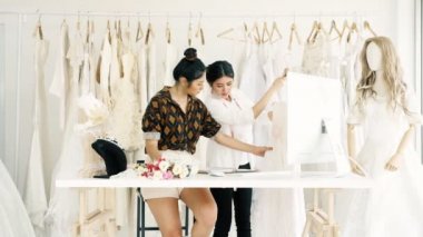 Birlikte çalışan genç moda evi tasarımcı. Bir gelinliğin gelin elbise arıyorum genç Asyalı kadın. Küçük işletme kavramı.
