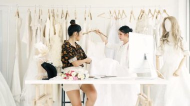 Birlikte çalışan genç moda evi tasarımcı. Bir gelinliğin gelin elbise arıyorum genç Asyalı kadın. Küçük işletme kavramı.