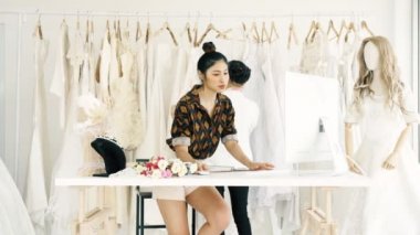 Birlikte çalışan genç moda evi tasarımcı. Bir gelinliğin gelin elbise arıyorum genç Asyalı kadın. Küçük işletme kavramı.