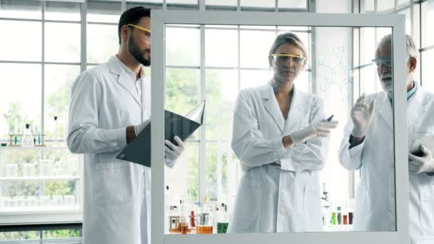 化学実験室での作業のグループ 小さなホワイト ガラスのディスプレイで書いて白人化学研究室で一緒に作業をシニアと男性と女性の化学者 科学のコンセプト — ストック動画