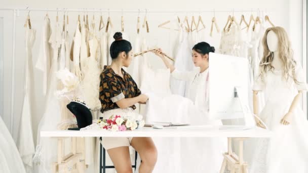 若者のファッション家のデザイナーが一緒に働きます ブライダル ドレス 花嫁のドレスを見て若いアジア女性 スモール ビジネス コンセプト — ストック動画