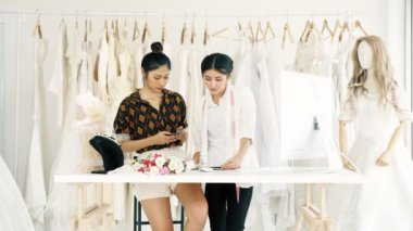 Çalışan genç moda evi tasarımcı. Gelin elbise, Evet ve müşteriler emir alan genç Asyalı kadın ile bilgisayar. Küçük işletme kavramı.