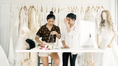 Birlikte çalışan genç moda evi tasarımcı. Genç Asyalı kadın düğün elbise aksesuarları ve kolye bakarak. Küçük işletme kavramı.