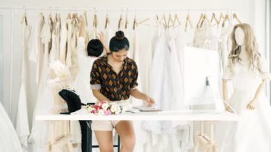 Birlikte çalışan genç moda evi tasarımcı. Bir gelinliğin gelin elbise arıyorum genç Asyalı kadın. Küçük işletme kavramı.