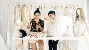 Birlikte çalışan genç moda evi tasarımcı. Genç Asyalı kadın düğün elbise aksesuarları ve kolye bakarak. Küçük işletme kavramı.