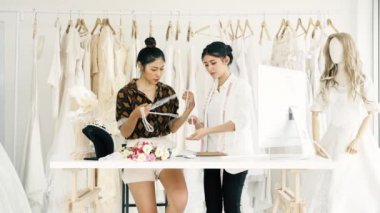 Birlikte çalışan genç moda evi tasarımcı. Genç Asyalı kadın düğün elbise aksesuarları ve kolye bakarak. Küçük işletme kavramı.