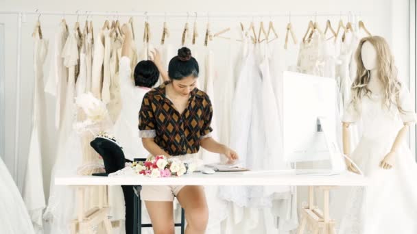 若者のファッション家のデザイナーが一緒に働きます ブライダル ドレス 花嫁のドレスを見て若いアジア女性 スモール ビジネス コンセプト — ストック動画