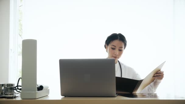 Junge Asiatische Ärztin Sitzt Auf Ihrem Schreibtisch Und Untersucht Das — Stockvideo