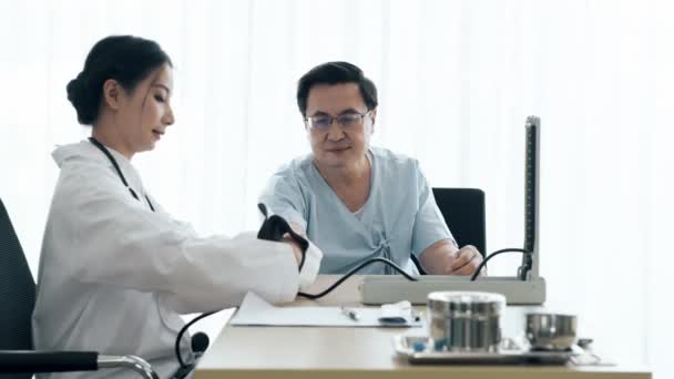 患者と医者 若い女性医師シニア患者病院で血圧を測定する話 介護医療と保険の概念 — ストック動画