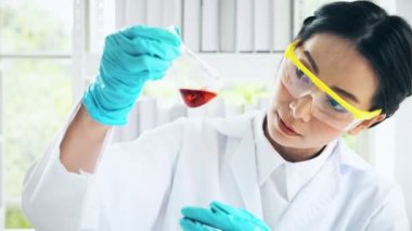 Asya kimyager bir laboratuarda çalışan. Genç kadın kimyager kimyasal sıvı test flak içinde incelemek, atış yakın. Bilim kavramı.
