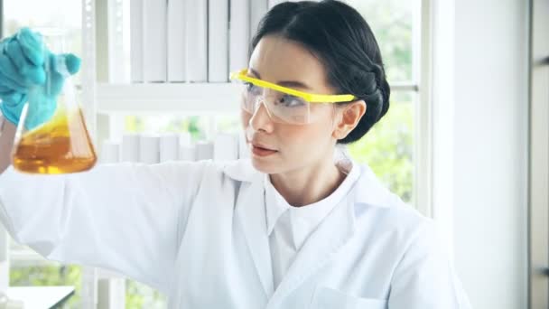 アジアの化学者の実験室での作業します 若い女性化学者は対空射撃テストで薬液を調べる クローズ アップ ショット 科学のコンセプト — ストック動画