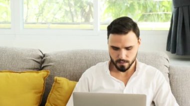Young couple working together at home on sofa using laptop, discussing work. White man and woman. Freelance concept.\