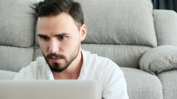 坐在地板上的年轻人在笔记本电脑上工作 专注于他的工作 有胡子的白人男性 自由职业的概念 — 图库视频影像