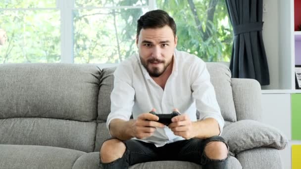 年轻人在摄像机前玩着游戏机 在网上击败了对手 坐在沙发上的白人 电子体育竞赛概念 — 图库视频影像