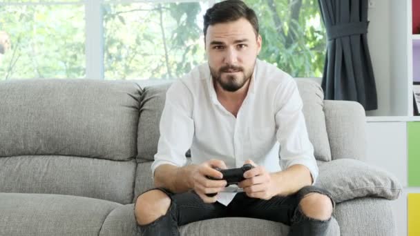 年轻人在摄像机前玩着游戏机 在网上击败了对手 坐在沙发上的白人 电子体育竞赛概念 — 图库视频影像
