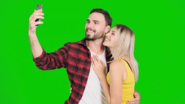 Yeşil ekran ve öpücük kadınla selfie çekici bir genç adam. Beyaz erkek ve kadın, chroma anahtar.