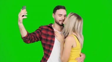Yeşil ekran ve öpücük kadınla selfie çekici bir genç adam. Beyaz erkek ve kadın, chroma anahtar.