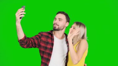 Yeşil ekran ve öpücük kadınla selfie çekici bir genç adam. Beyaz erkek ve kadın, chroma anahtar.