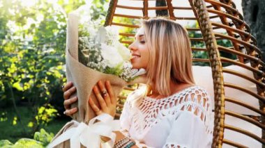 Genç kadın koku beyaz çiçek oturma park güneşte karşı. Bahar, yaz vibe. Romantik kavramı.