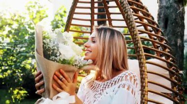 Genç kadın koku beyaz çiçek oturma park güneşte karşı. Bahar, yaz vibe. Romantik kavramı.