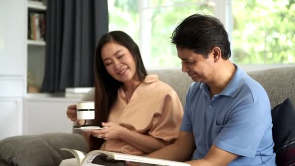 Hombre Asiático Mayor Leyendo Libro Hermosa Esposa Sala Estar Concepto — Vídeo de stock