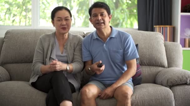 亚洲高级男子在电视上与他美丽的妻子在客厅里观看足球比赛 老年人生活方式退休概念 — 图库视频影像