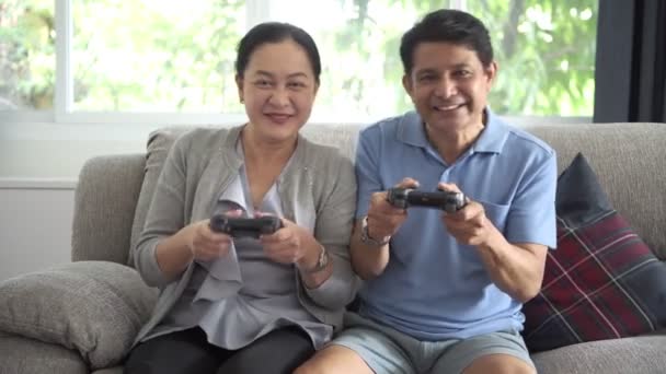 幸せの居間で一緒にテレビにコンソール ゲームをプレイ上級アジア カップルの笑顔します シニアのライフ スタイル コンセプト — ストック動画