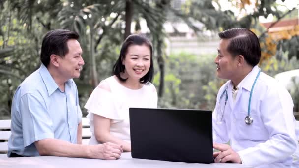 上級アジア医師の庭屋外上級アジア カップルの健康を議論するラップトップを使用して 介護サービスのコンセプト — ストック動画