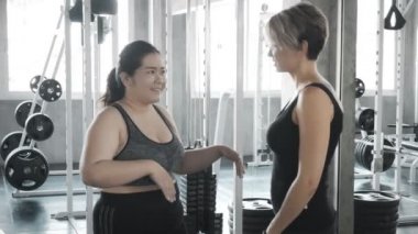 Şişman kadın spor salonunda antrenörü ile konuşuyor