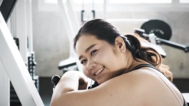 Genç şişman Asyalı kadın portresi. Arka planda jimnastik salonu ile bankta oturmak. Otantik Fitness yaşam tarzı konsepti.
