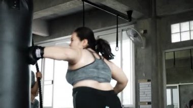 Şişman kadın spor salonunda bir kum torbası boks