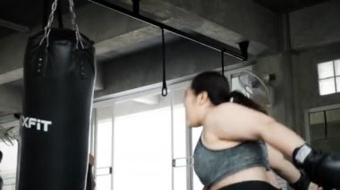 Şişman kadın spor salonunda bir kum torbası boks