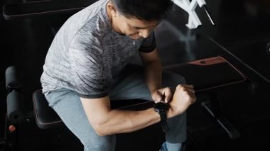 Spor salonunda akıllı saat kullanan yaşlı adam.