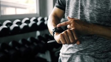 Spor salonunda akıllı saat kullanan yaşlı adam.